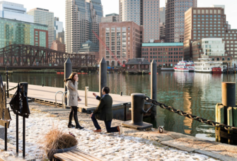Man proposing to woman in front of Boston skyline