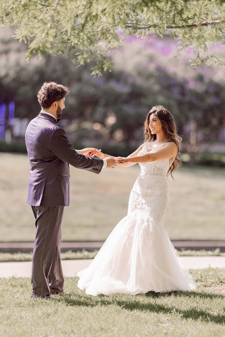 Groom in Navy Tuxedo Holds Hands With Bride in Lace Trumpet Wedding Dress Outside