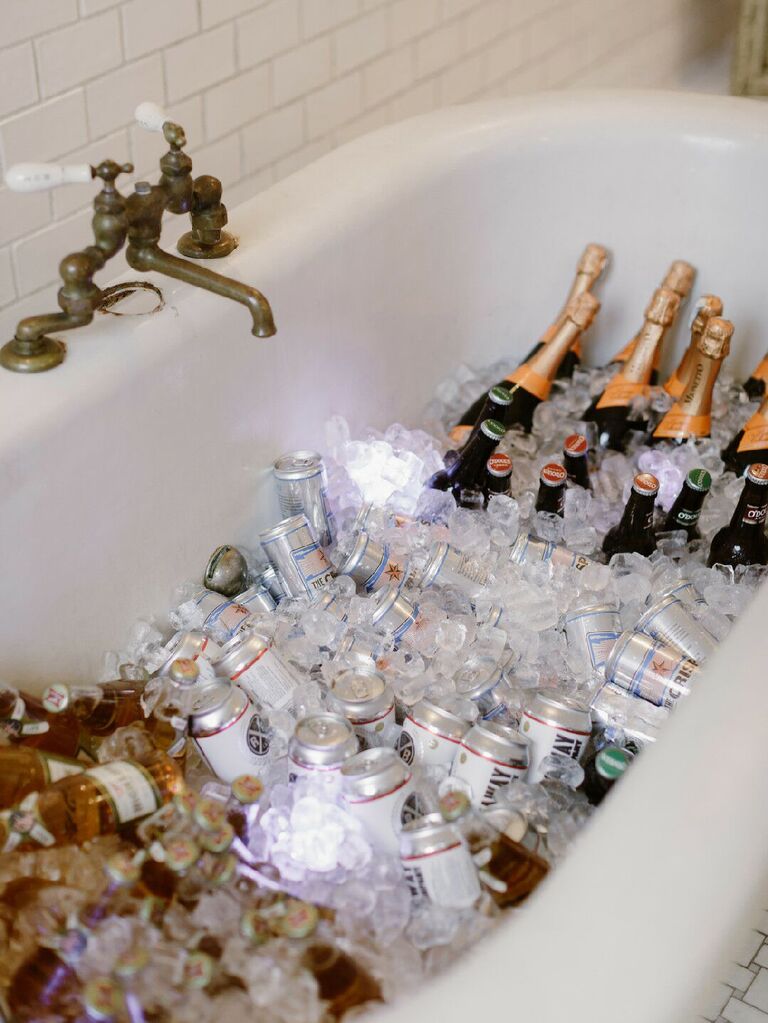 Champagne and beer in ice-filled bathtub at modern glam wedding