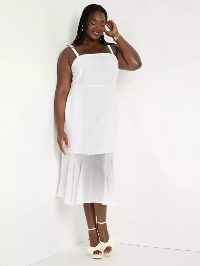 A model shows off this fun and flirty white dress with a sheer hem.