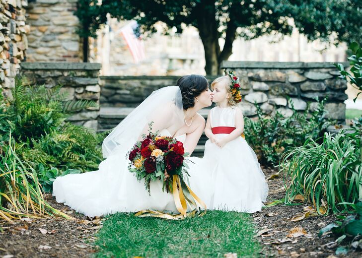 The flower girl wore a classic white dress with a red ribbon tied around the waist. A flower crown in the day's autumnal color palette completed the look.