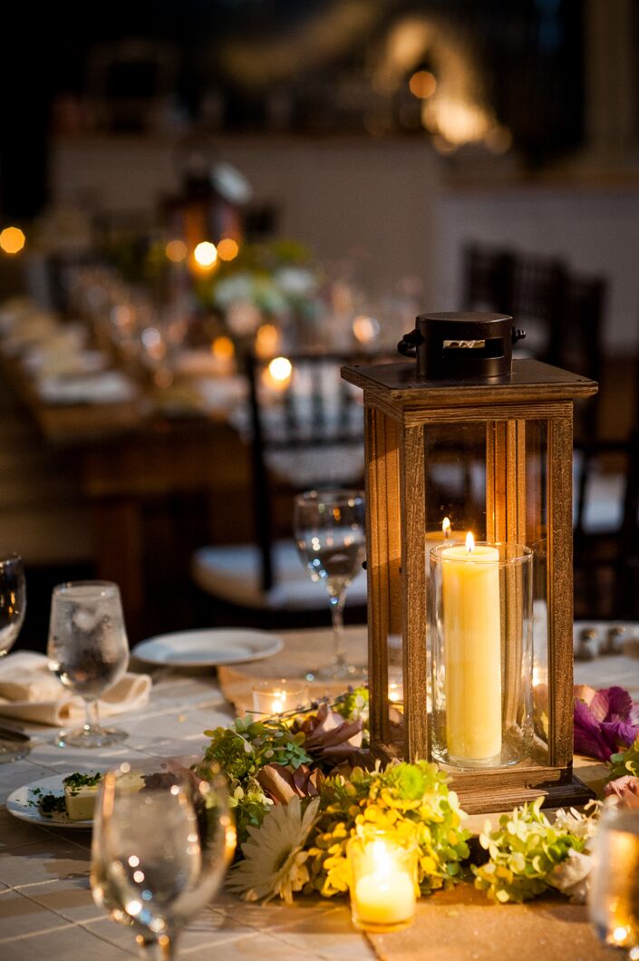 Black lanterns with candles were wreathed with hydrangeas, viburnum, gerber daisies and other flowers to create the centerpieces at the reception.