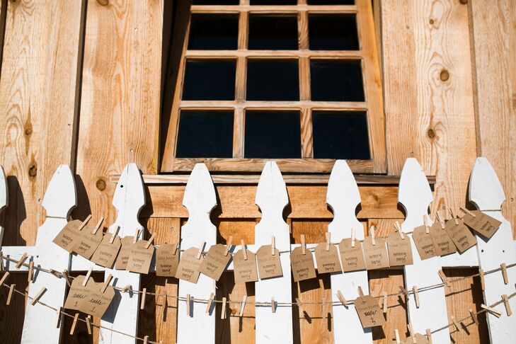 Kraft-paper escort tags tangled from wire, strung across a white picket fence that leaned against the barn at Amador Cellars in Plymouth, California. This display followed the day's rustic-chic theme and country style.