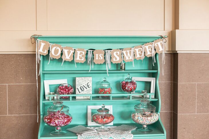Brittney and Josh had a turquoise vintage cabinet candy bar filled with sweets for their guests. A rustic "love is sweet" banner continued the shabby-chic theme.