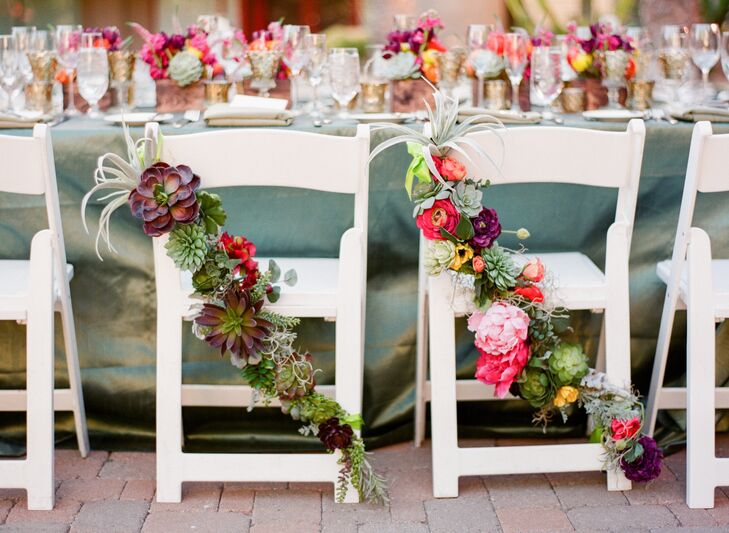 Flowers from Kelsey's bouquet of succulents with magenta garden roses, jasmine vine, yellow and orange ranunculus, plum   dendrobrium orchid blooms also worked to decorate chairs at the reception.