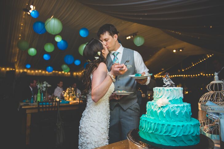 The tented reception was illuminated with string lights and green and blue lanterns. The cake was turquoise ombre with a glass bird topper.