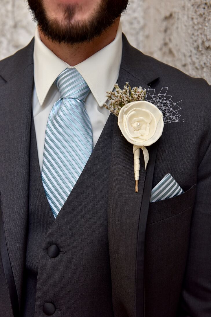 Lawrence had a single ivory fabric flower boutonniere accented with netting, which was pinned to the lapel of his charcoal gray three-piece suit. A pop of color was added through the blue-striped tie that had a matching pocket square.