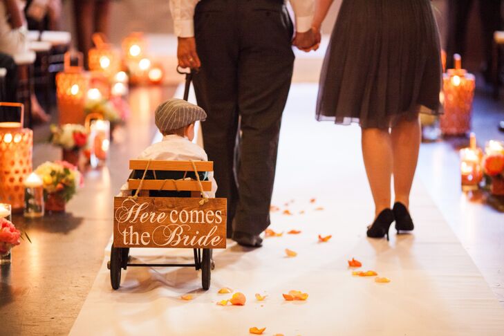 Since the ring bearer was too young to walk down the aisle, his parents pulled him in a little wagon behind the flower girl. His little cart was decorated with a wooden sign that said "Here Comes the Bride" on the back.