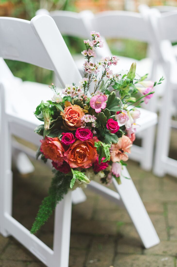 Orange and pink blooms filled the bouquets that marked the aisles at the ceremony.