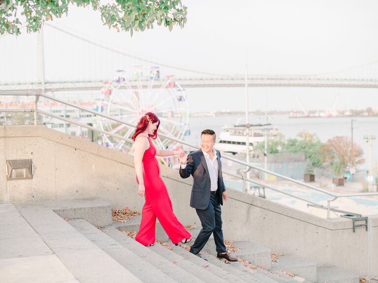 The happy newly-engaged couple take photos by a Ferris wheel