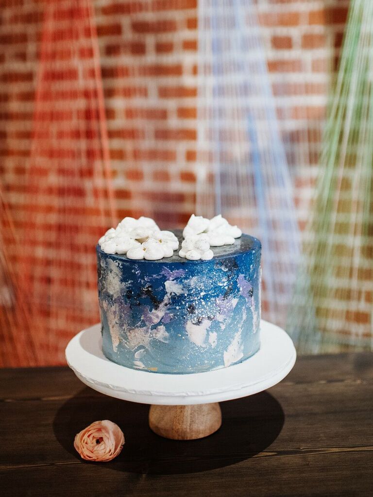 celestial one tier wedding cake with blue and purple design and white meringues as clouds on top