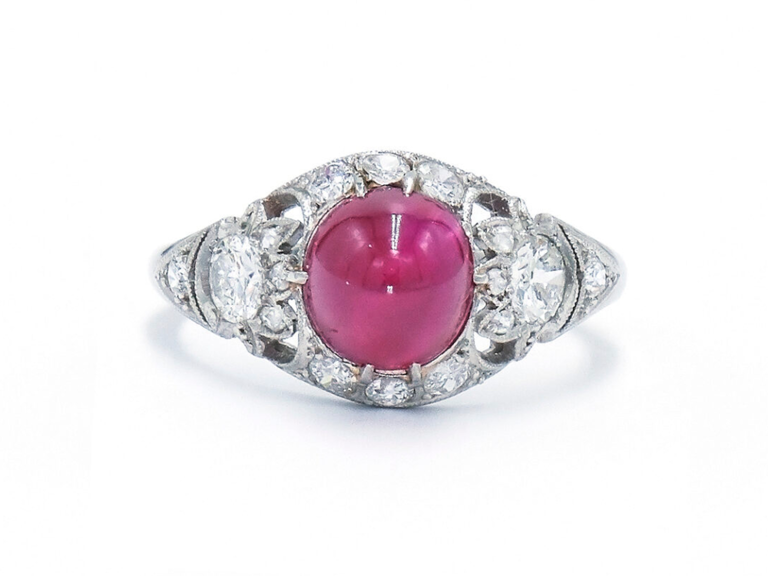 Round ruby center stone with diamond halo and oval diamonds on side