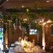 Dimly Lit Barn With Hanging Greenery and Lavender Flowers, Round Tables With Candles