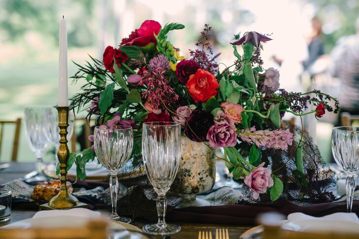 Gold mercury glass vases overflowing with textured blooms in rich hues livened the rustic wooden farm table. Tall gold candlesticks and low amber crystal tea candleholders continued the warm color theme.