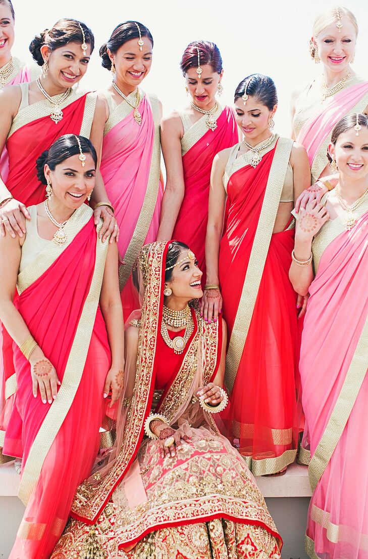 For the traditional South Indian Hindu ceremony, Melanie's bridesmaids matched her delicately embroidered lehenga in red or pink saris with gold trim. They each wore matching gold necklaces and tikka headpieces.