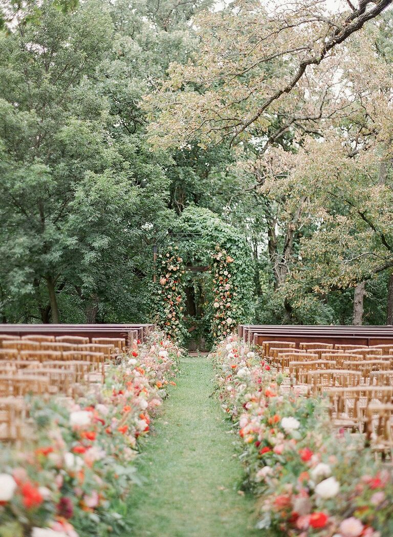 Outdoor wedding ceremony with floral-lined aisle and floral arch