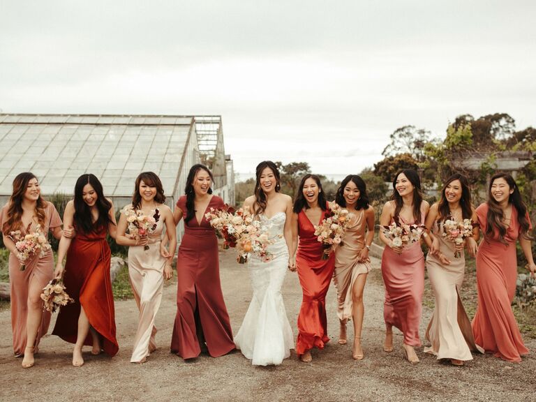 Bridesmaids wear dresses in various shades of pink and red. 