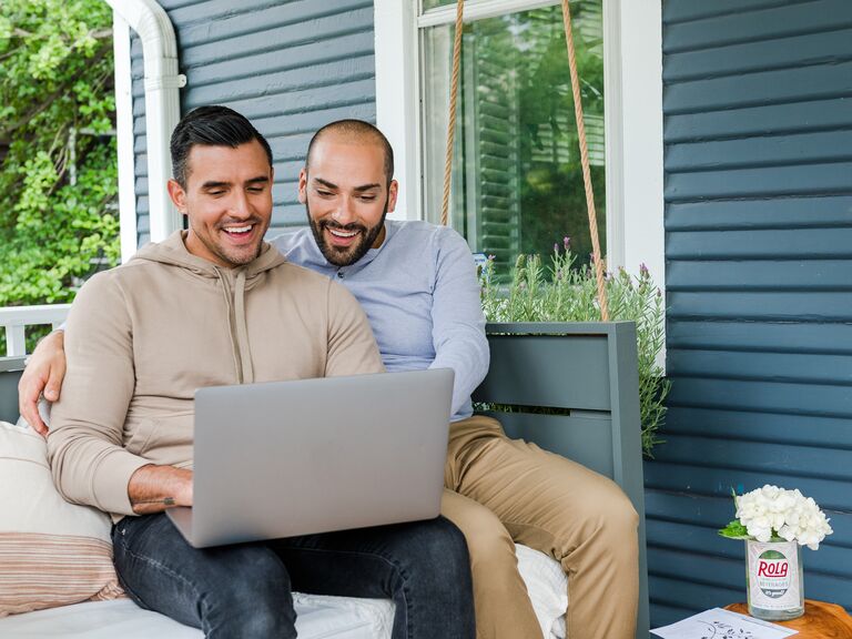 Couple sitting on porch swing looking at laptop