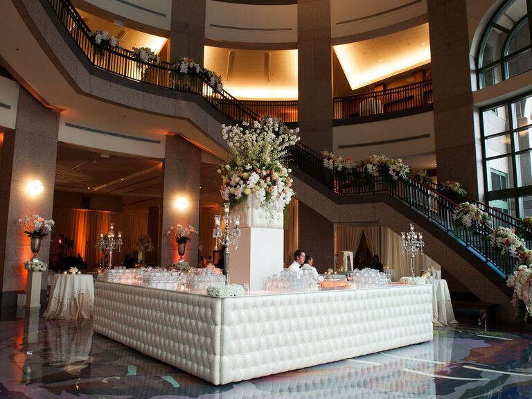 White upholstered wedding bar space with floral arrangements