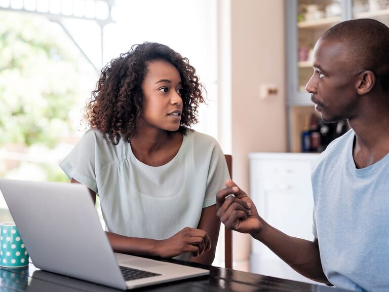 Couple talking to each other at home with laptop doing online couples therapy