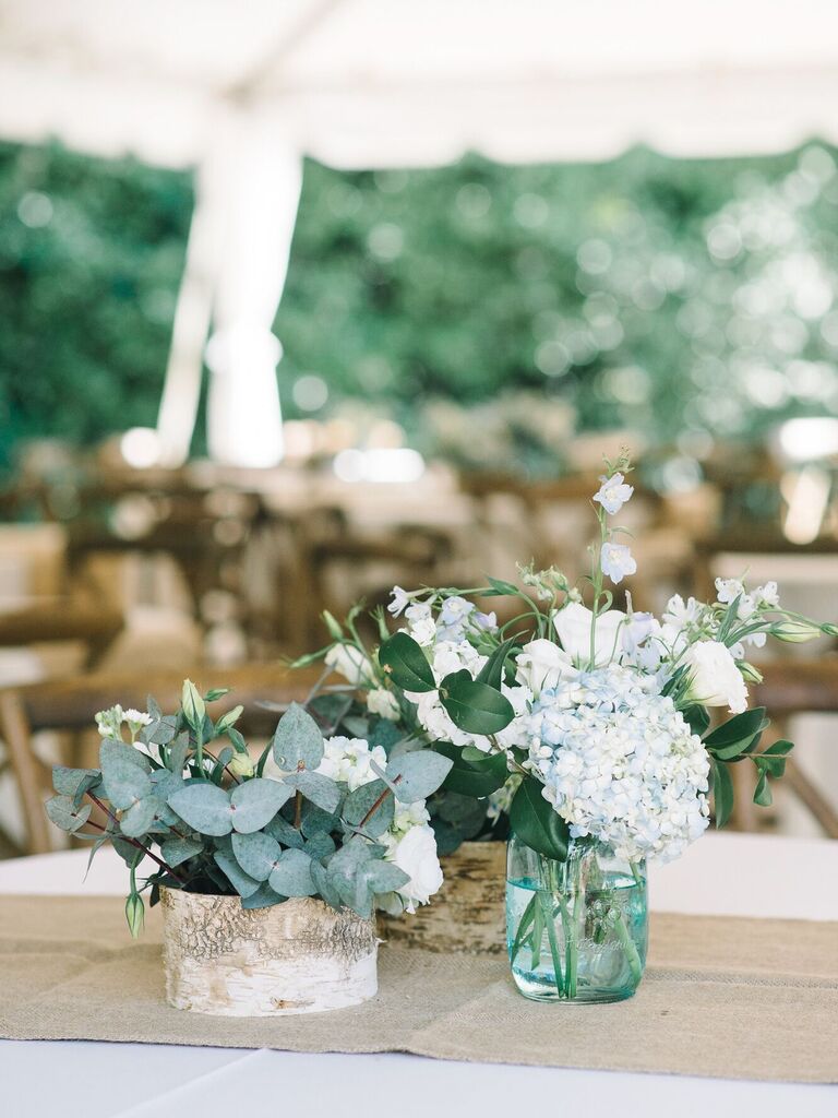 short rustic wedding centerpieces with eucalyptus, blue hydrangeas and wooden vessels