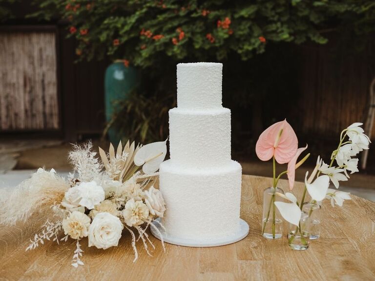 white wedding cake beside boho anthurium flower arrangement