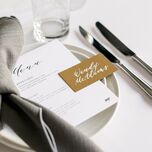 modern wedding reception place setting with gray tied napkin and gold place card with white calligraphy