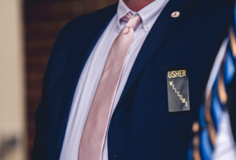 Man in blue suit with usher badge