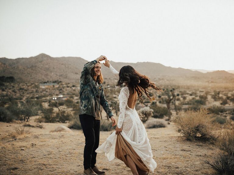 Bohemian bride and groom dancing in desert on wedding day