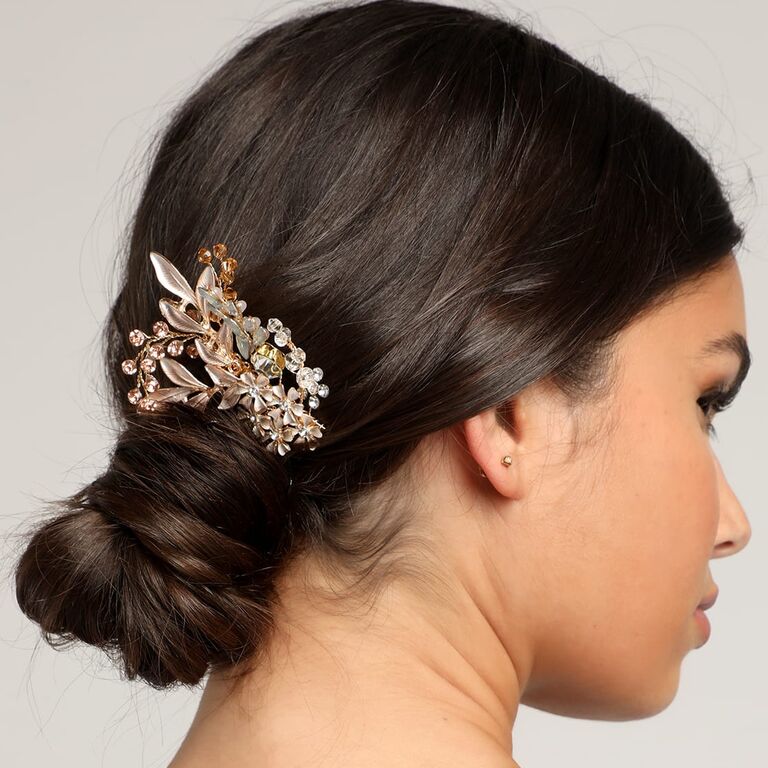Model wears a bedazzled hair clip in a low bun. 