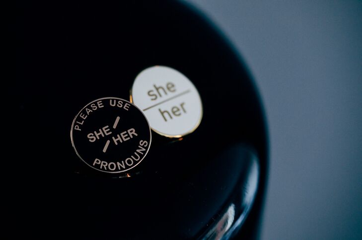 Custom-made buttons for each guest at an Art Deco, rooftop wedding in New York City that display guests' pronouns during the event: She/Her pronouns, They/Them pronouns, He/Him pronouns etc. in black-and-white available before the LGBTQ+ wedding ceremony.