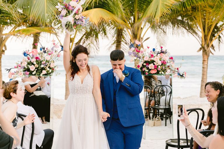 couple holding hands and recessing from beach ceremony