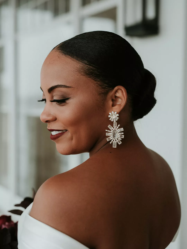 A bride wears diamond art deco drop earrings.