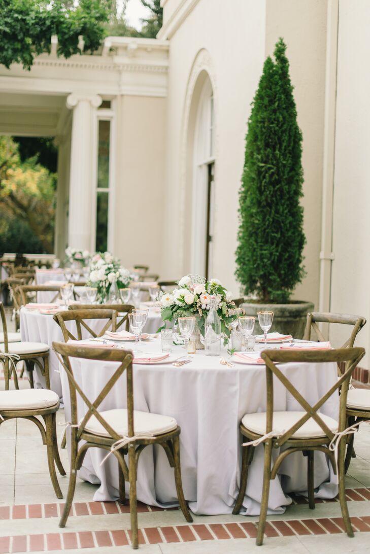 Light gray linen-covered tables were set with gold-­accented ivory china, elegant gold flatware and gold­-rimmed glassware. Atop each place setting sat a peach napkin and a dinner menu with dusty blue font. Vintage glass water bottles with white script numbers served as table identifiers.