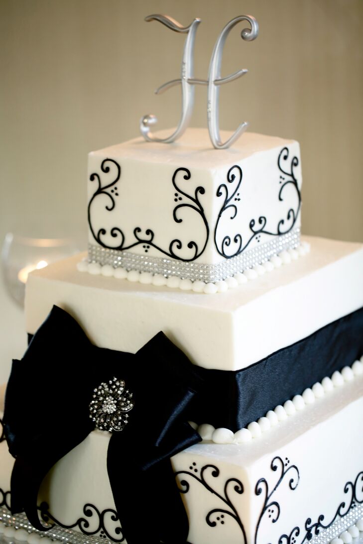 The three-tiered wedding cake was decorated with black design and wrapped with thick black ribbon. The cake topper was the couple's last name initial.