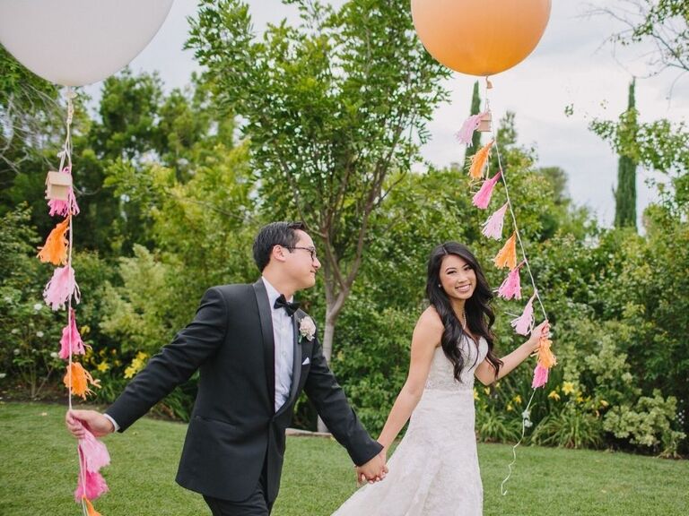 bride and groom holding balloons as wedding bouquet alternative