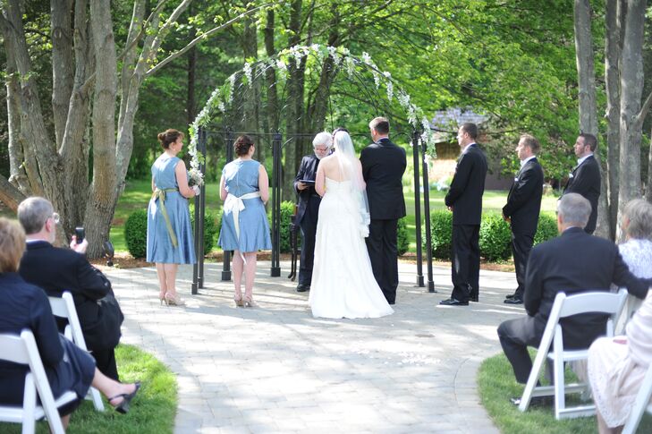 Heather and Chris were married under a wedding arch decorated with greens and blue flowers at their outdoor ceremony in Branford, Connecticut.
