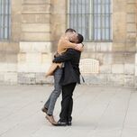 two men smile and embrace as a couple