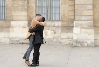 two men smile and embrace as a couple