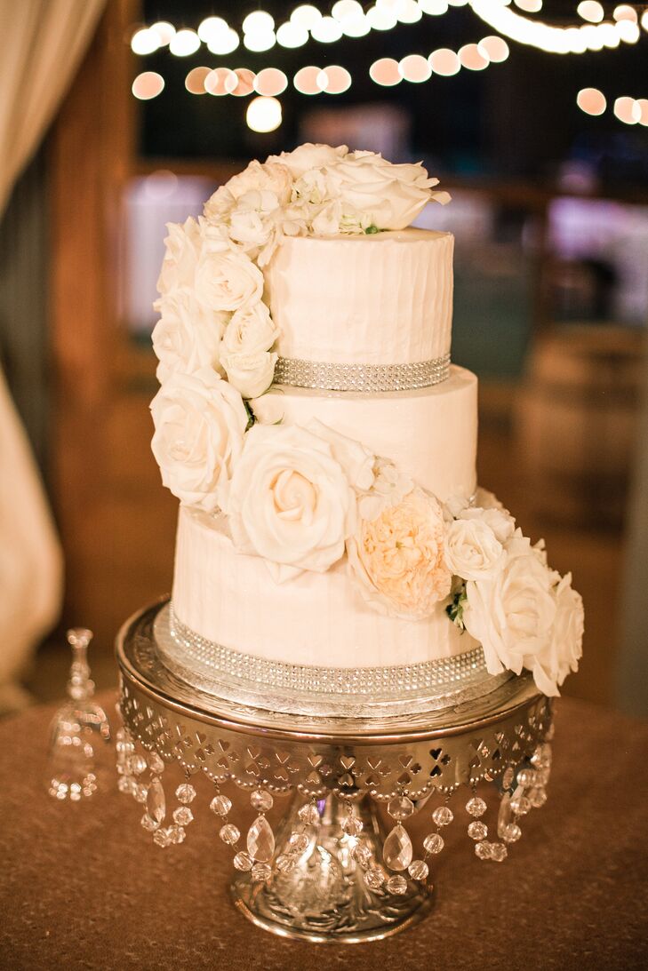 Nikki and Scott enjoyed a three-tier white wedding cake with raspberry filling. Silver rhinestones wrapped around the base of each layer, and the cake was topped with cascading white roses.