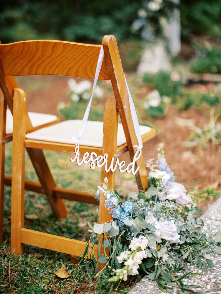 A whimsical reserved sign hanging off of the front row of wood chairs at a couple's garden party wedding ceremony in Savannah, Georgia.