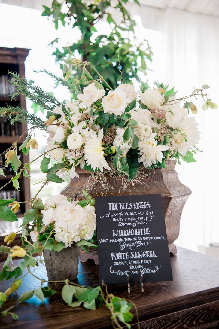 A black-and-white chalkboard sign displayed the speciality cocktail options, set up in front of a large overflowing arrangement filled with ivory blooms.