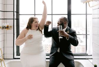 bride and groom toasting champagne in bathtub