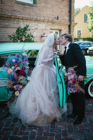 A Bride in a Blush Wedding Dress Kisses Groom as From a Blue Car