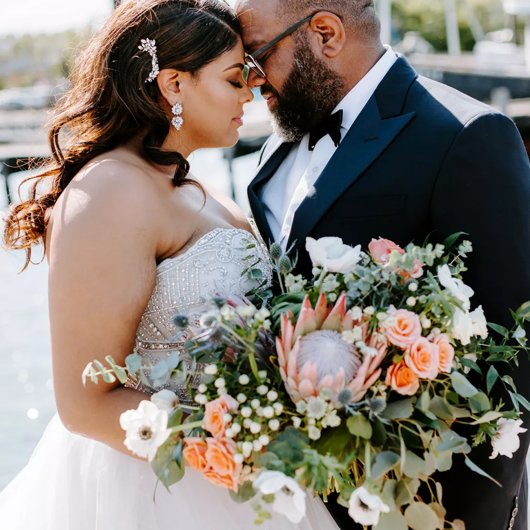 A peach-toned wedding bouquet with roses and proteas