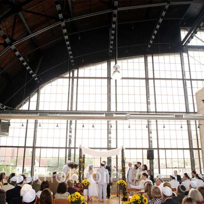 Natural light shone in through the floor-to-ceiling windows for the couple’s morning ceremony. Sunflowers added color along the aisle.