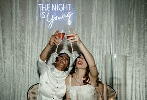 Couple Toasting During Reception Beside Neon Sign