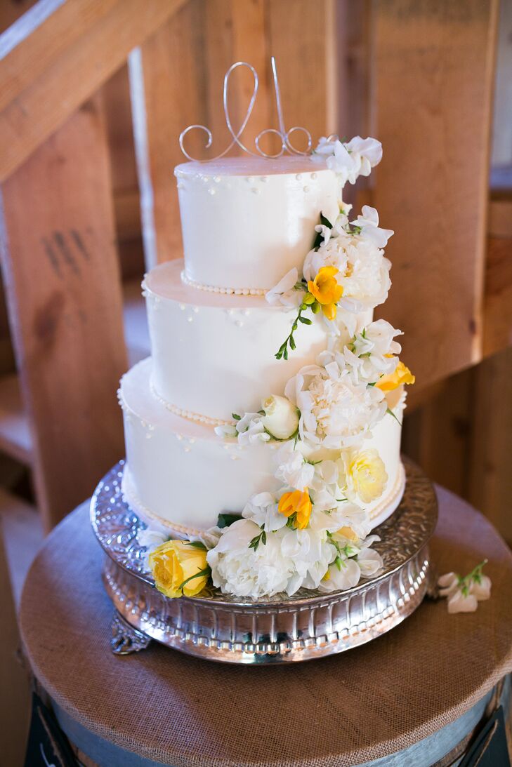 Fresh white and yellow flowers scaled the three-tier white wedding cake from top to bottom, propped up on top of an elegant silver stand. The entire sweet display embodied the white, yellow and silver color scheme seen throughout the celebration.