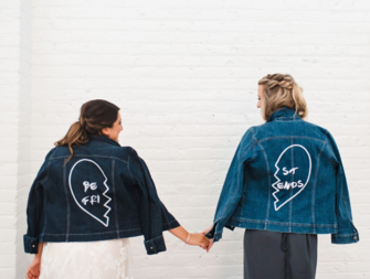 Bride and maid of honor holding hands wearing matching denim jackets