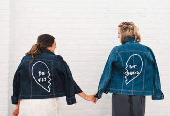 Bride and maid of honor holding hands wearing matching denim jackets